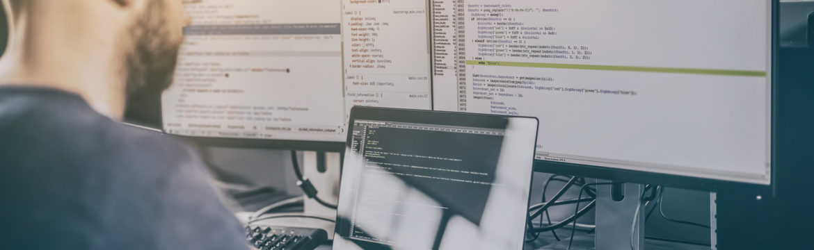 man sitting at desk writing programming code