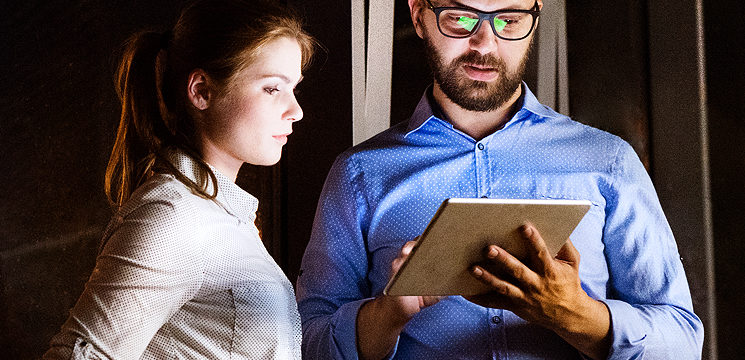 two coworkers looking at a tablet