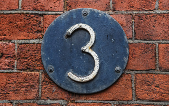 3 Digit on Dark Metal Background on red brick wall