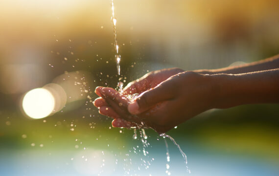 Closeup shot of hands held out under a stream of water